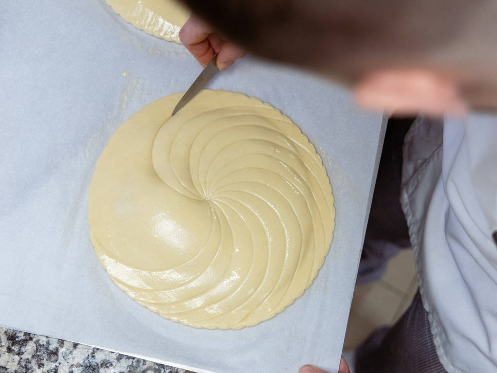 La phase de décoration se poursuit sur la partie supérieure de la galette, toujours à la façon Pithiviers. La galette est ensuite dorée au pinceau avant de reposer au frigo pendant 12 heures. Il est à présent temps de cuire la galette.